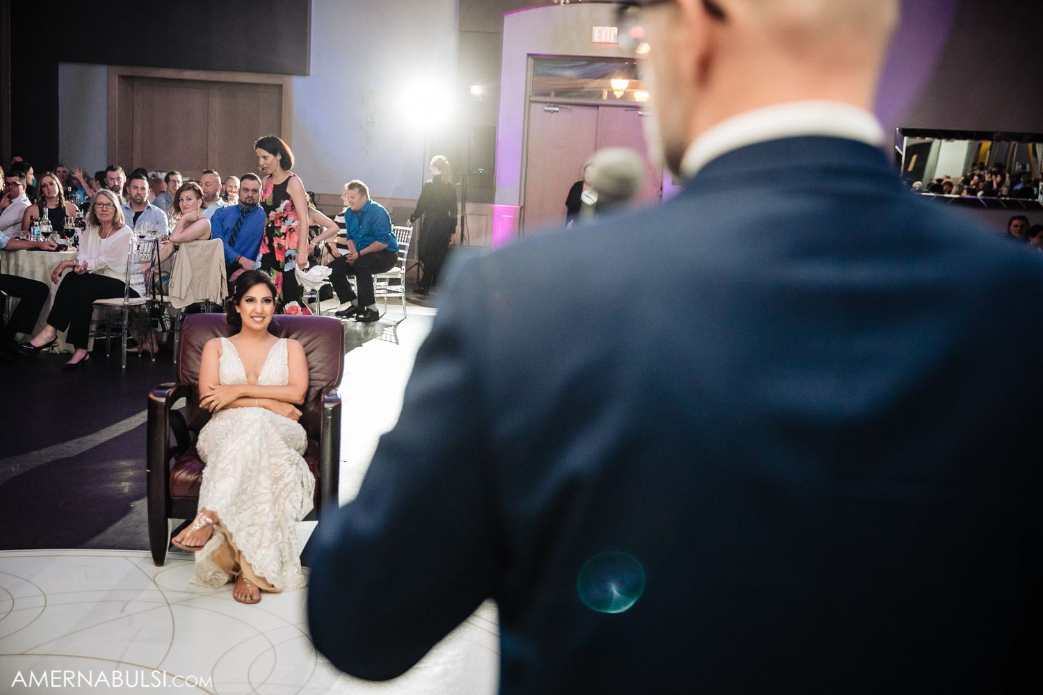 Wedding reception dance floor captured in dramatic lighting with guests celebrating.
