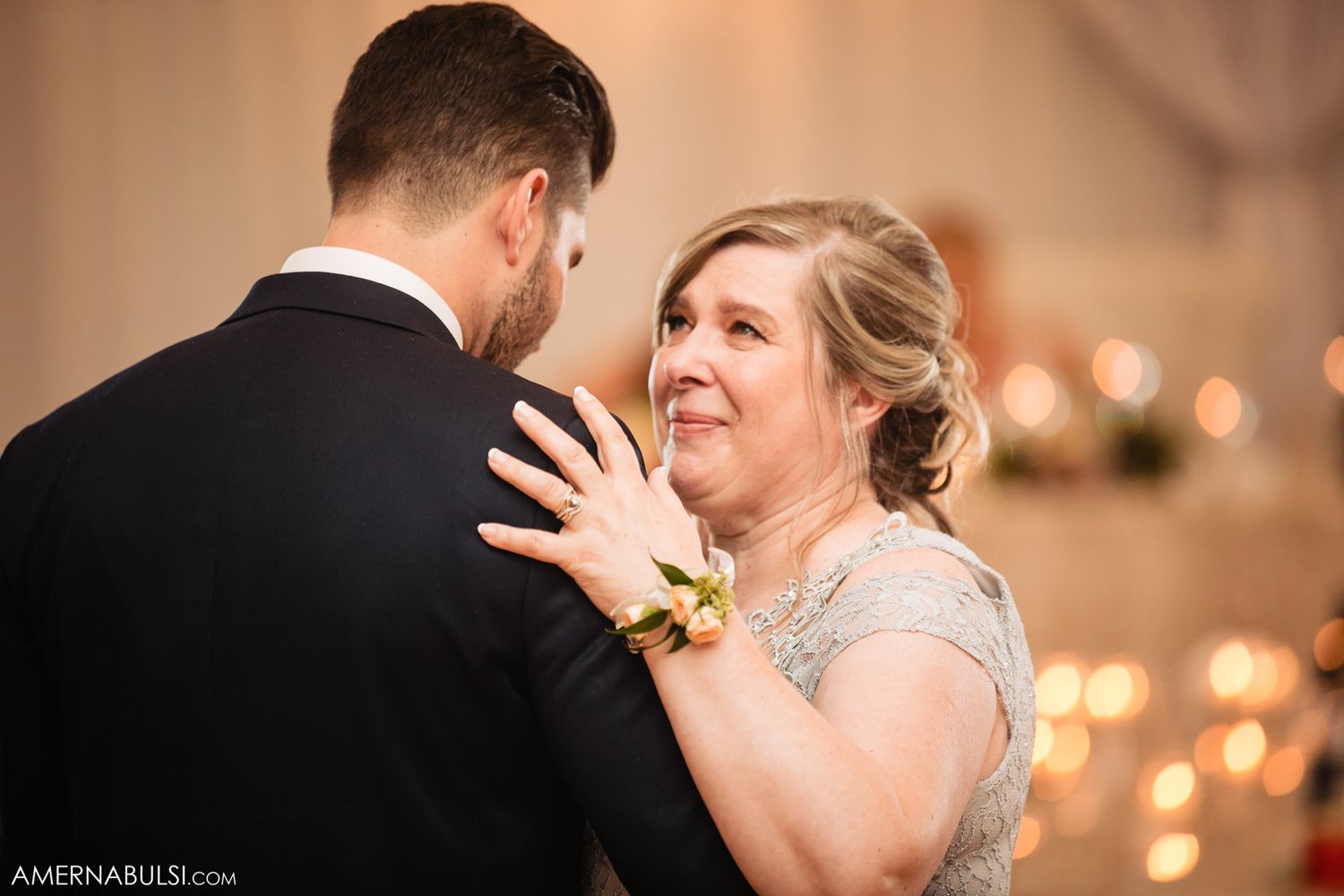 A romantic wedding dance moment captured with soft bokeh lights in the background during an evening reception.