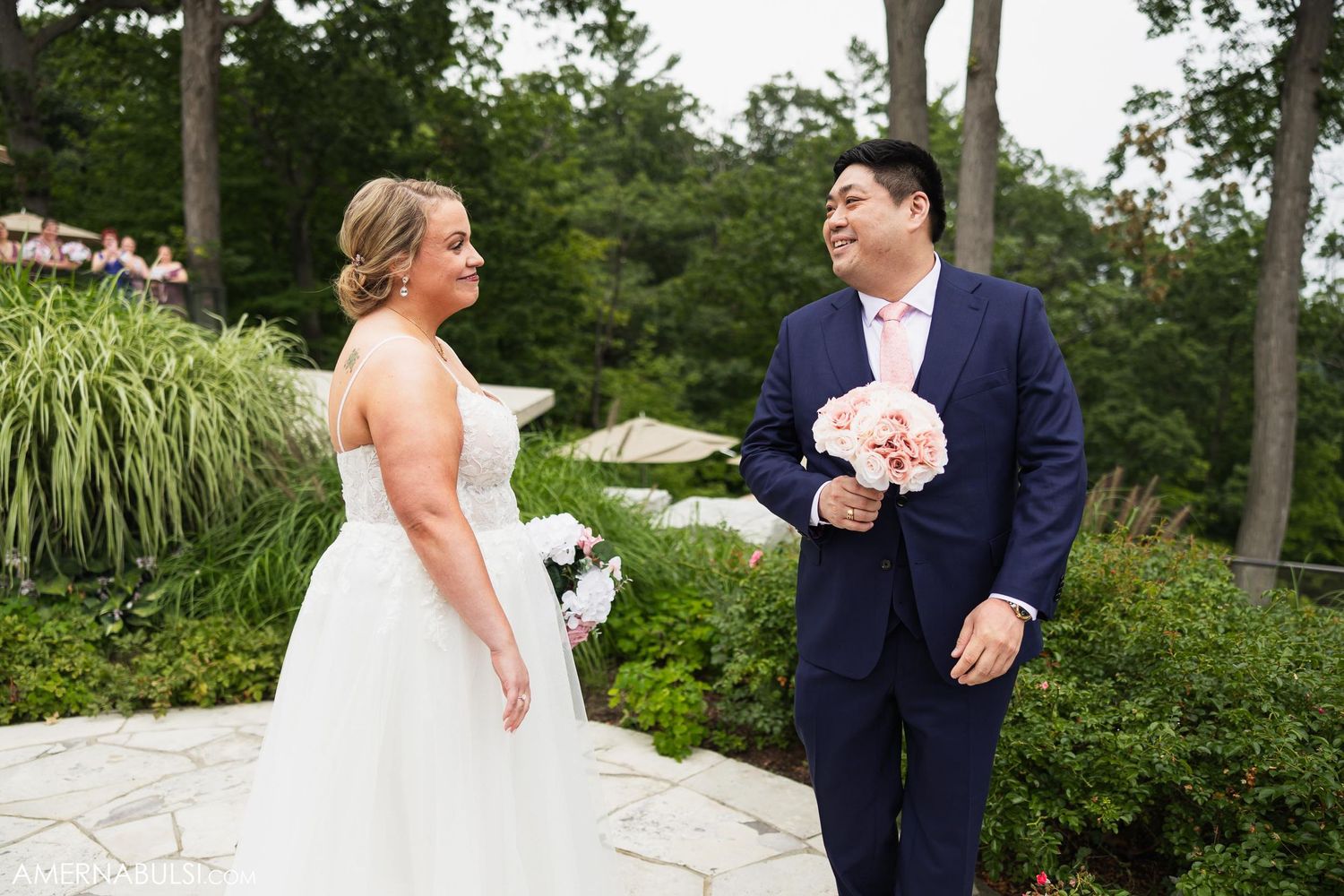 Couple shares laughter during their first look on a stone patio.
