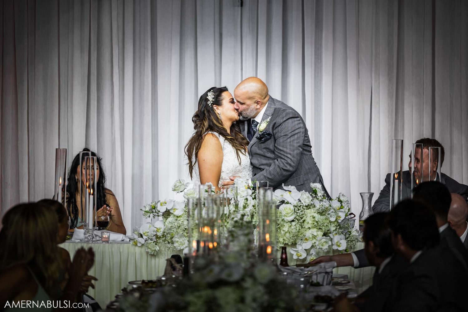 Romantic moment at wedding reception with table decorated in white flowers and candles.