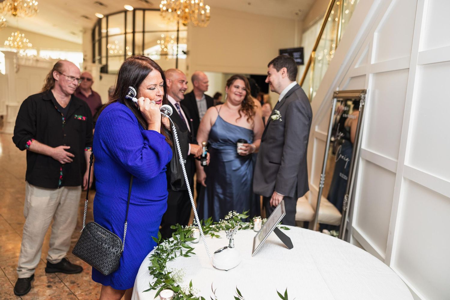 Wedding guests gathered around a decorative table sharing an exciting moment.