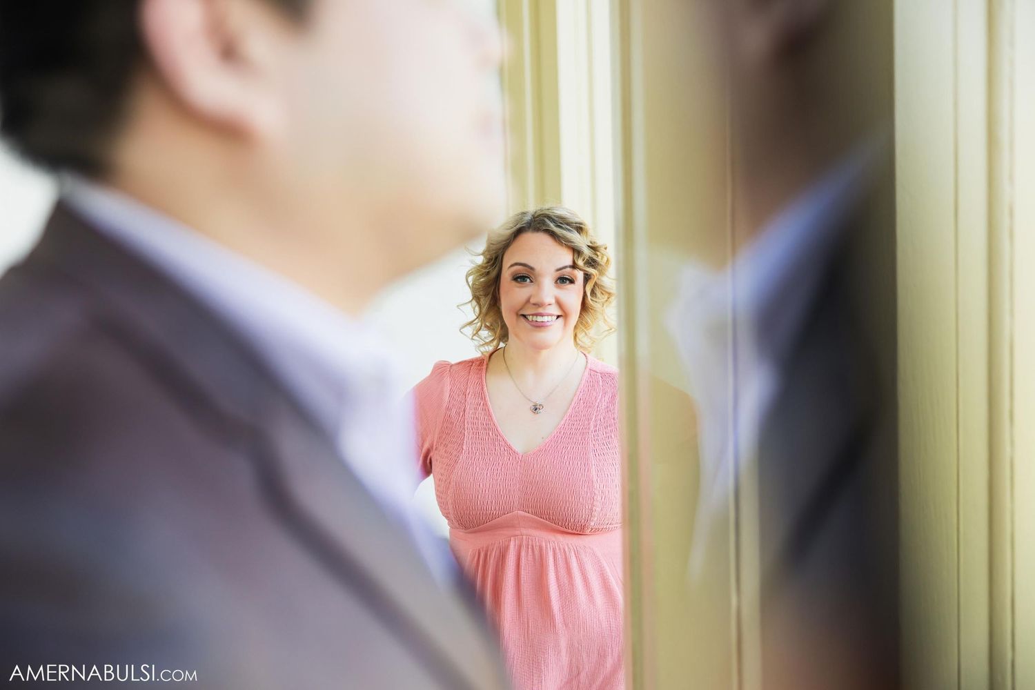 A reflection in a window shows a couple during their engagement photoshoot.