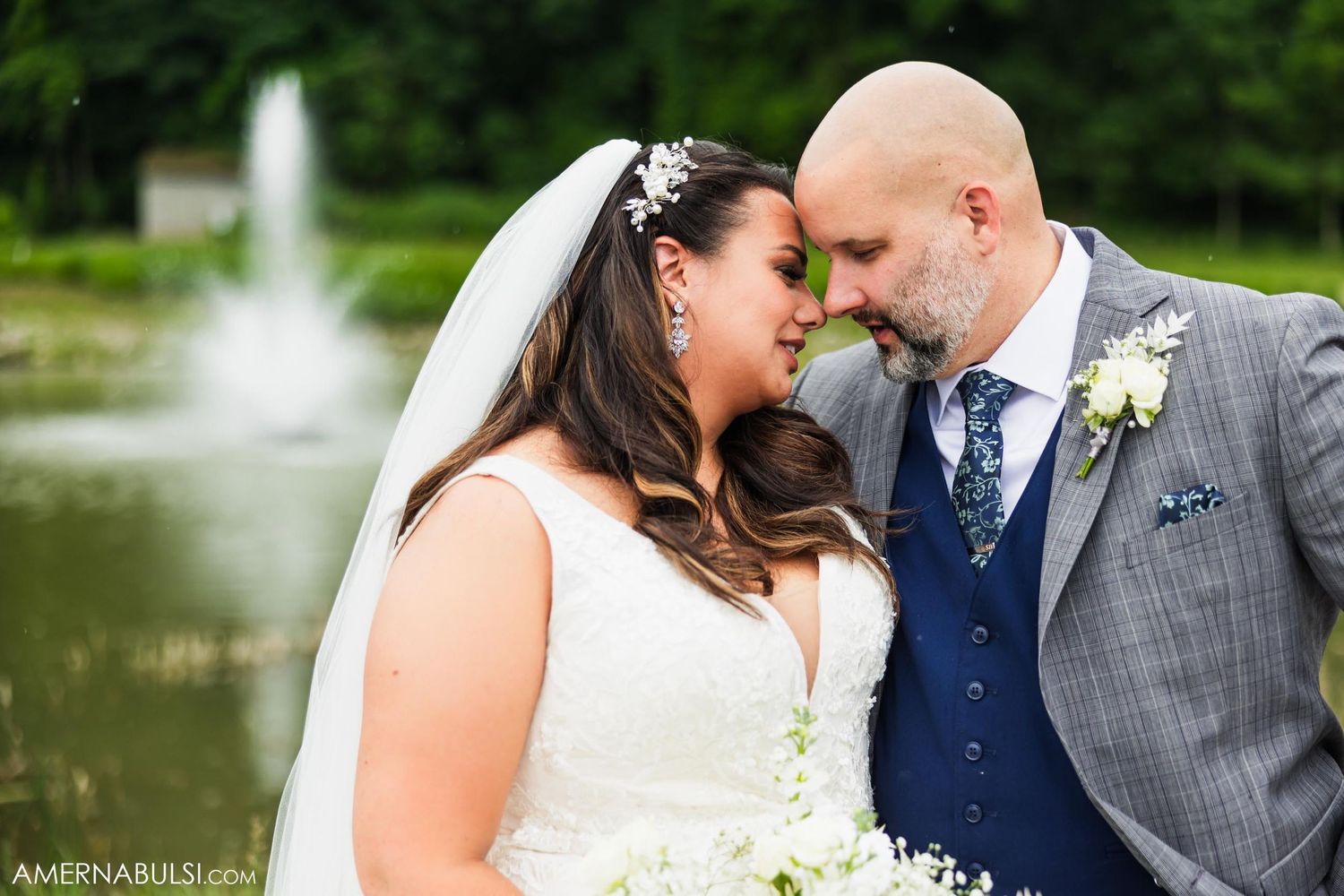 Intimate moment between newlyweds by fountain during outdoor portrait session.