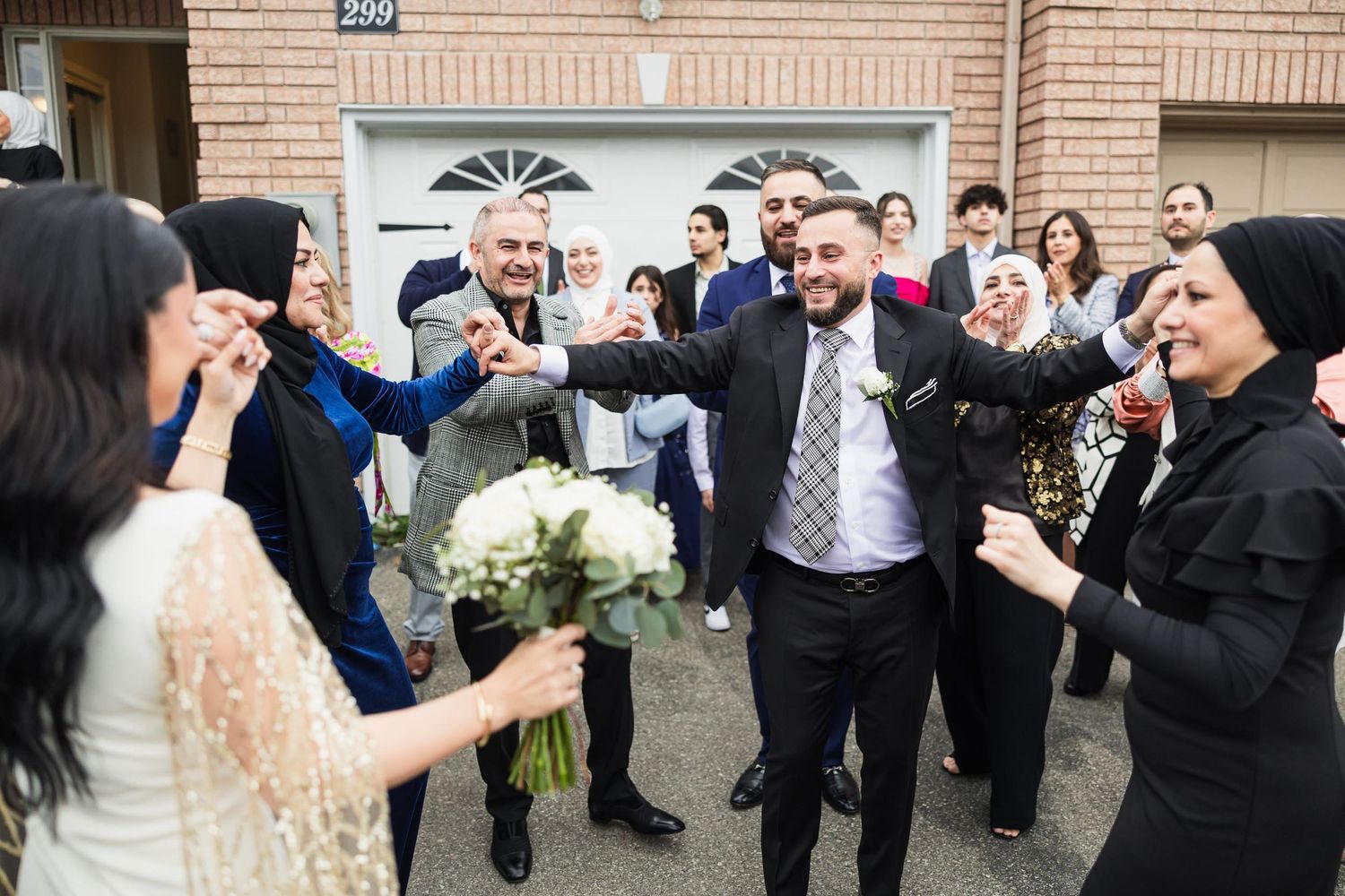 A celebratory moment at a wedding with guests cheering outdoors in front of a brick building.