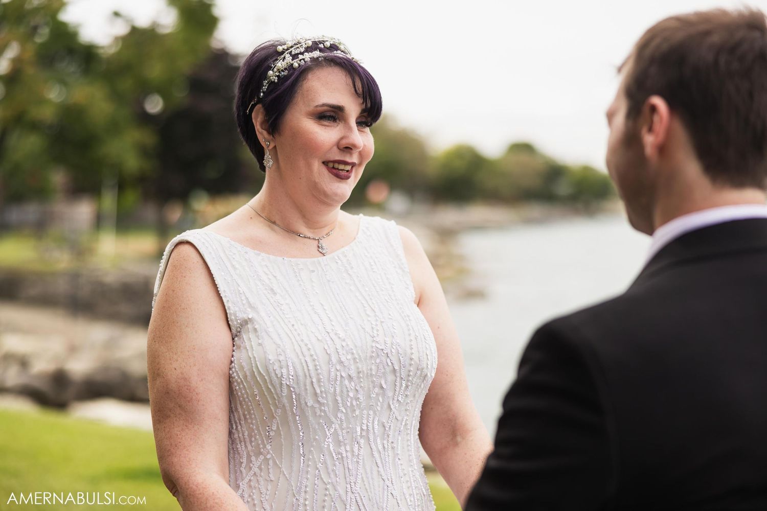 Joyful exchange between couple during waterfront wedding ceremony.