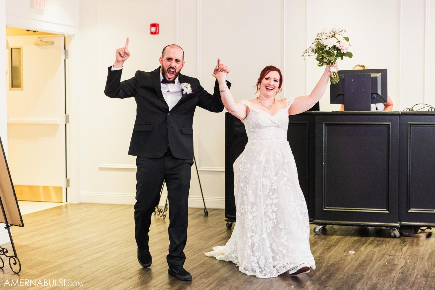 Newlyweds celebrate with joyful arms raised during their wedding reception.