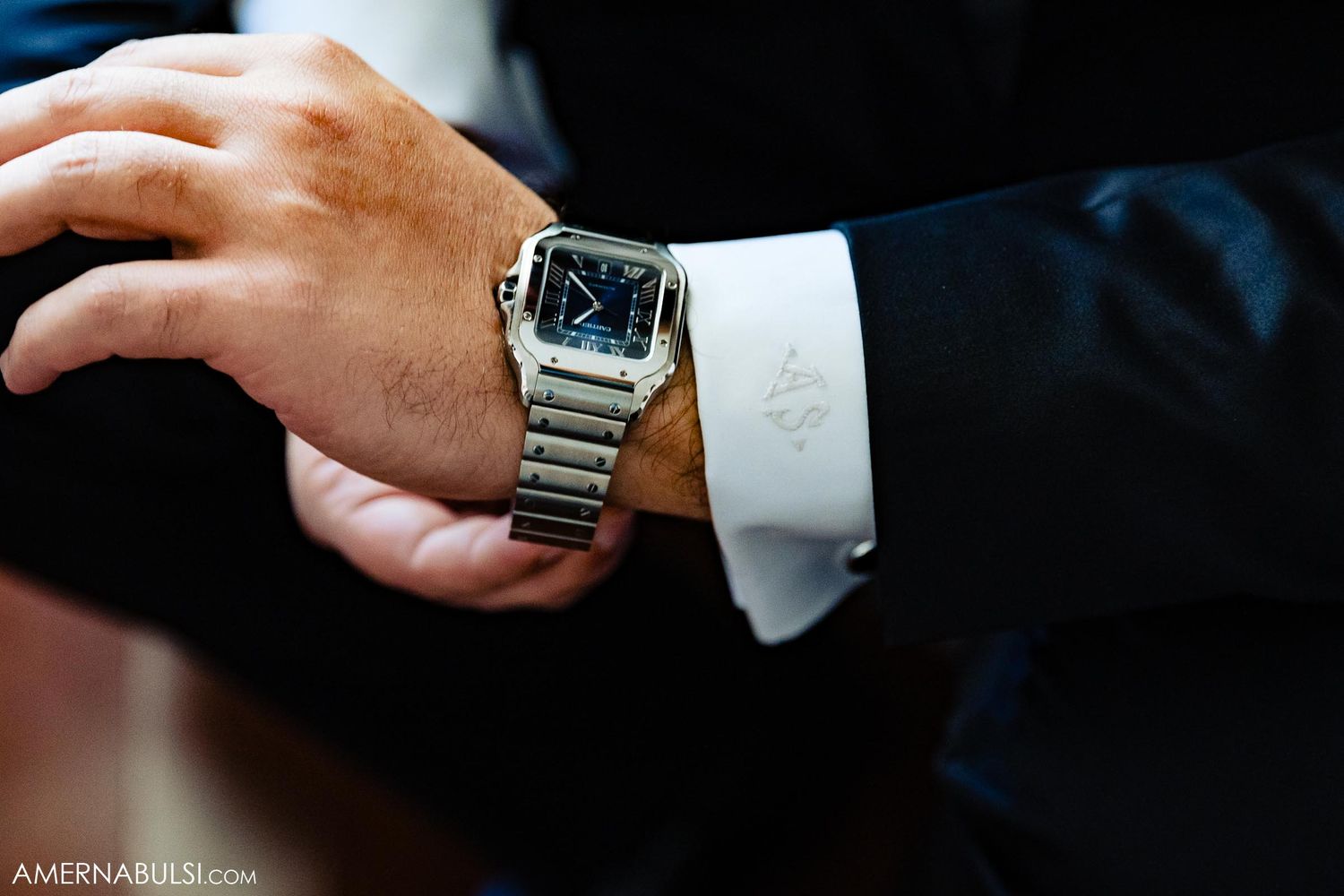 Close-up detail shot of elegant metal watch on formal suited sleeve.