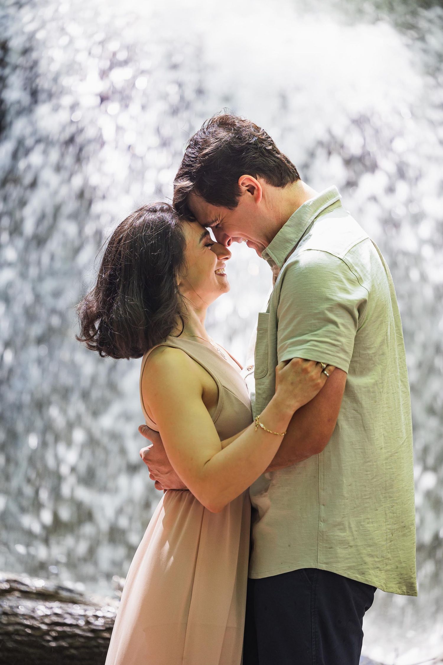 Romantic couple shares an intimate moment in front of a cascading waterfall.