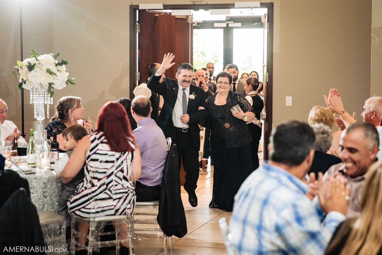 Wedding reception guests clapping and cheering during a celebration in a banquet hall.
