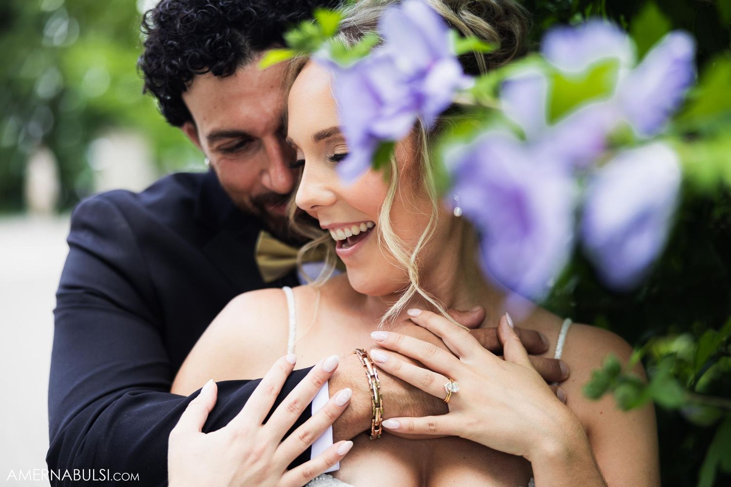 An intimate wedding portrait moment captured among blooming purple flowers in a garden setting.