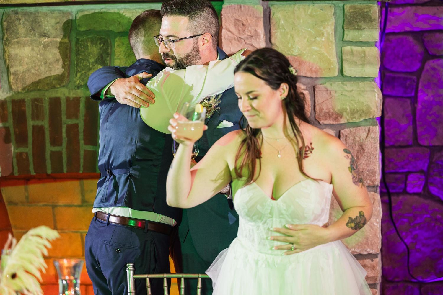 Wedding reception celebration with guests enjoying drinks in stone-walled venue.