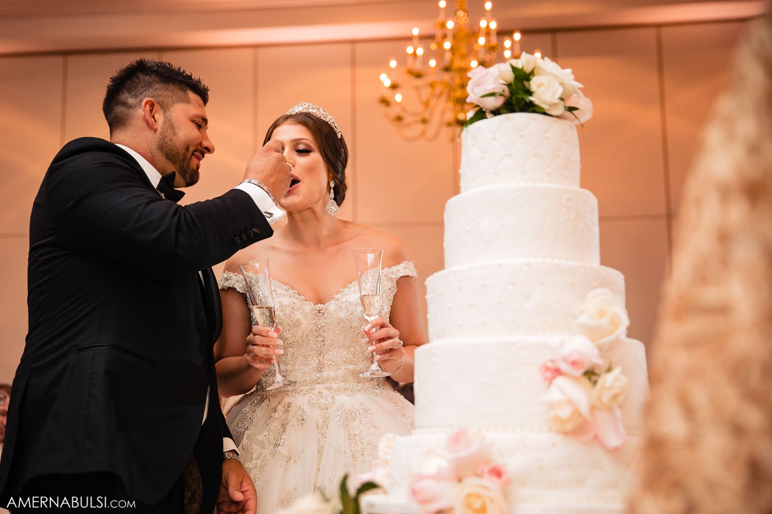 Wedding reception venue decorated with crystal chandeliers and white floral arrangements.