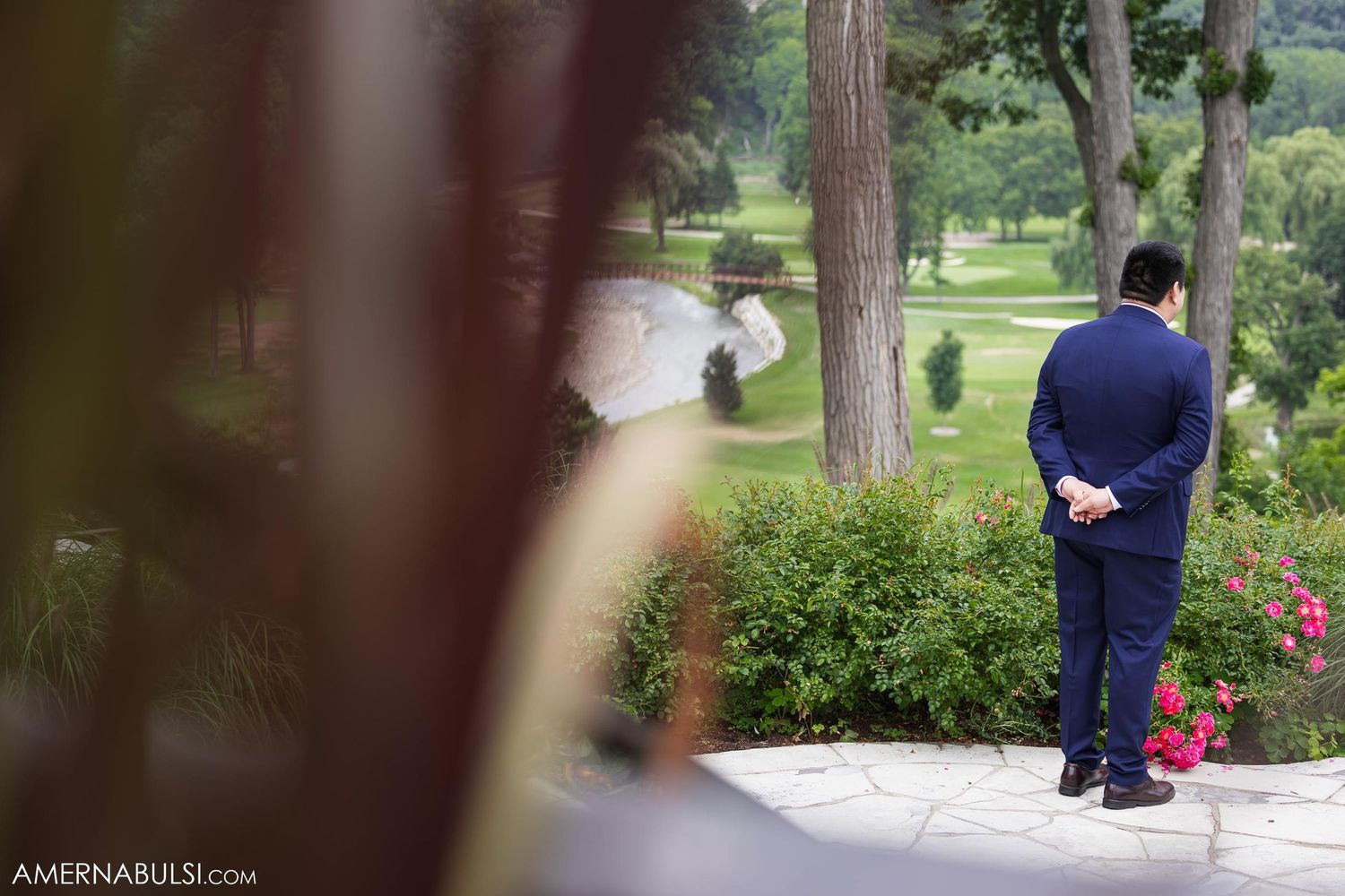 First look moment photographed through foliage at outdoor garden venue.