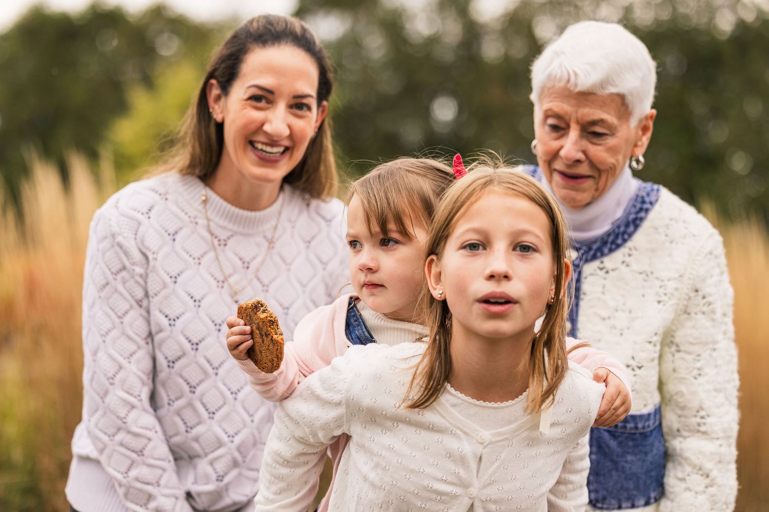 Family members laughing and smiling together while sitting outdoors in a park during golden hour.