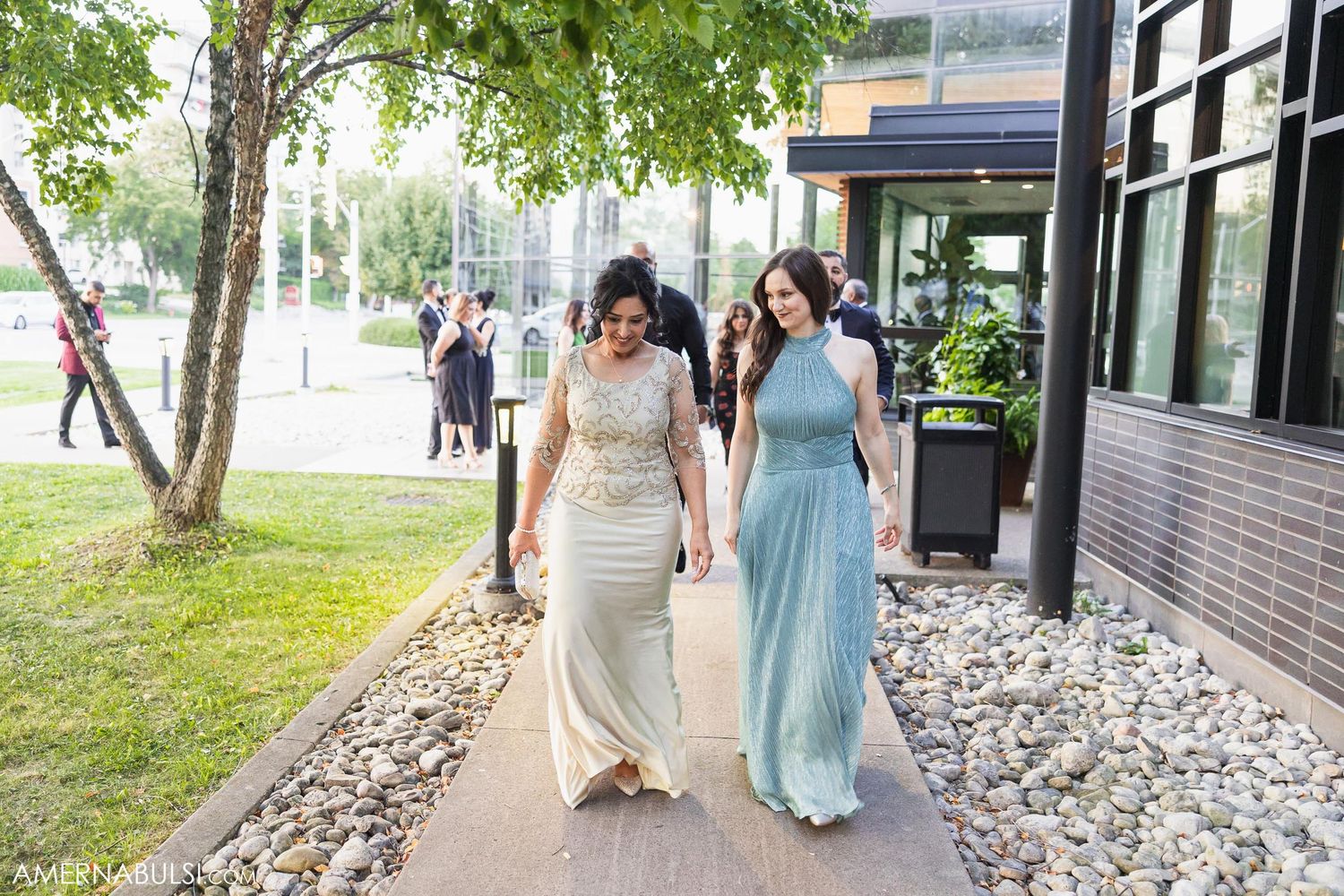 Two people in formal attire walking along an urban sidewalk.