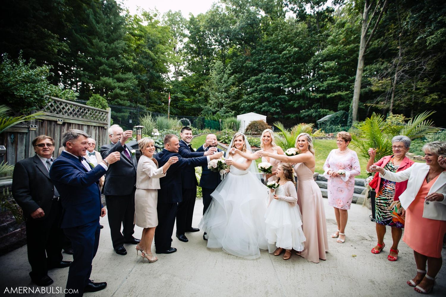 Wedding guests gather outdoors in a garden setting during a summer celebration.