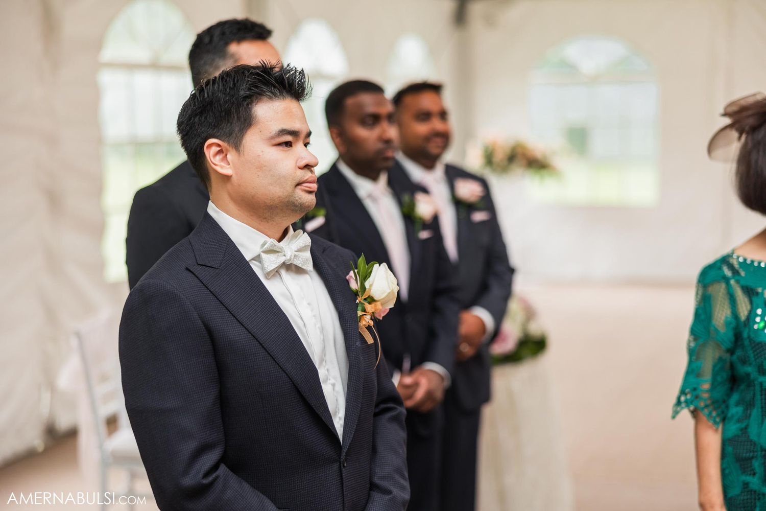 Formal wedding ceremony with groomsmen in black suits standing at the altar.