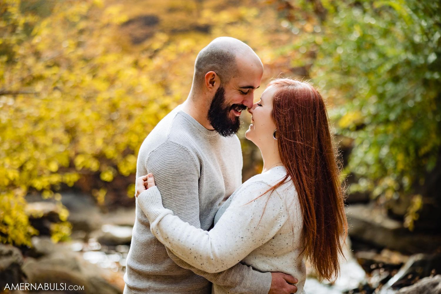 Couple sharing intimate moment against backdrop of autumn foliage.