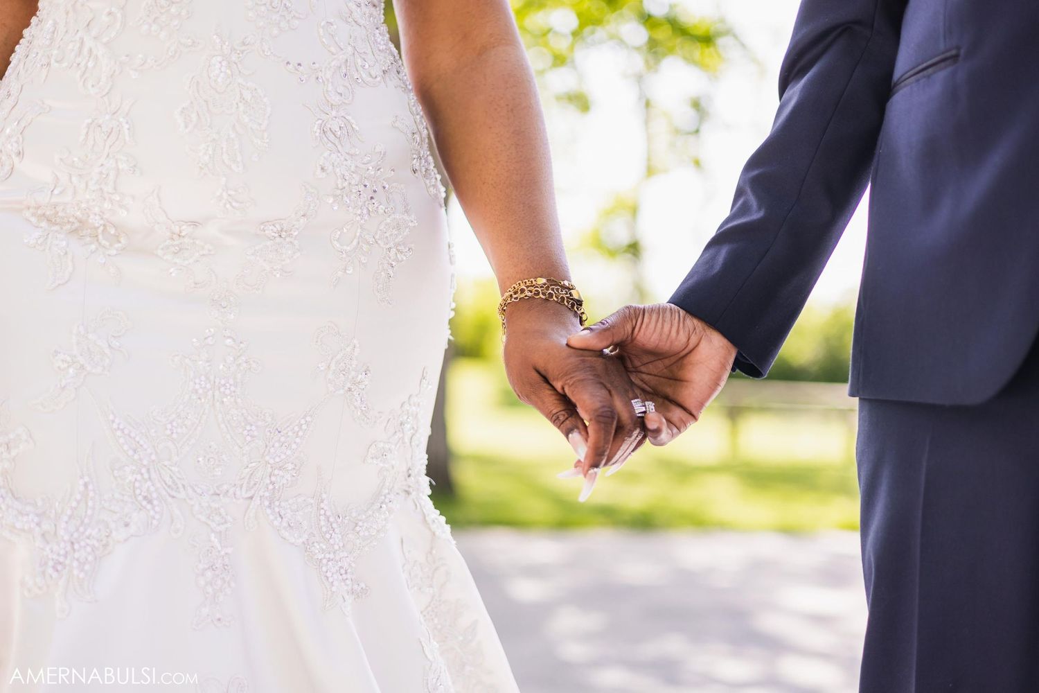 Close-up shot of newlyweds holding hands with wedding rings visible.