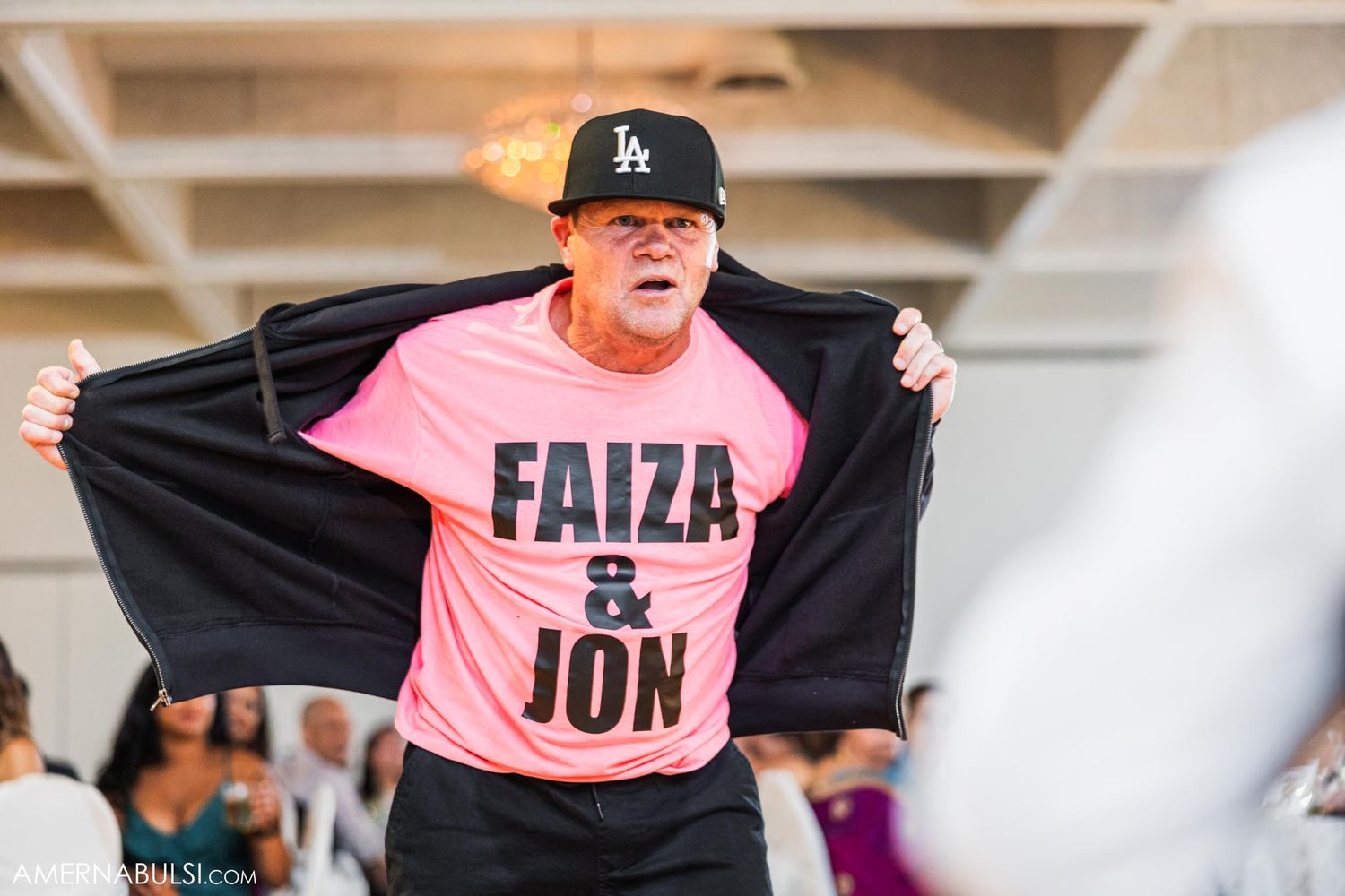 Guest wearing a pink t-shirt with text displaying enthusiasm at a wedding reception.
