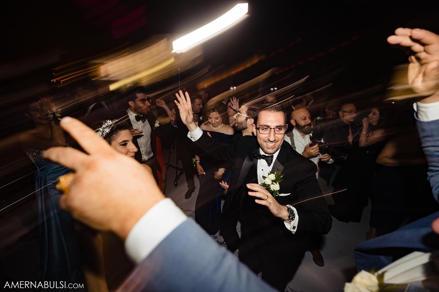 Wedding guests dancing and jumping enthusiastically at a lively reception party.