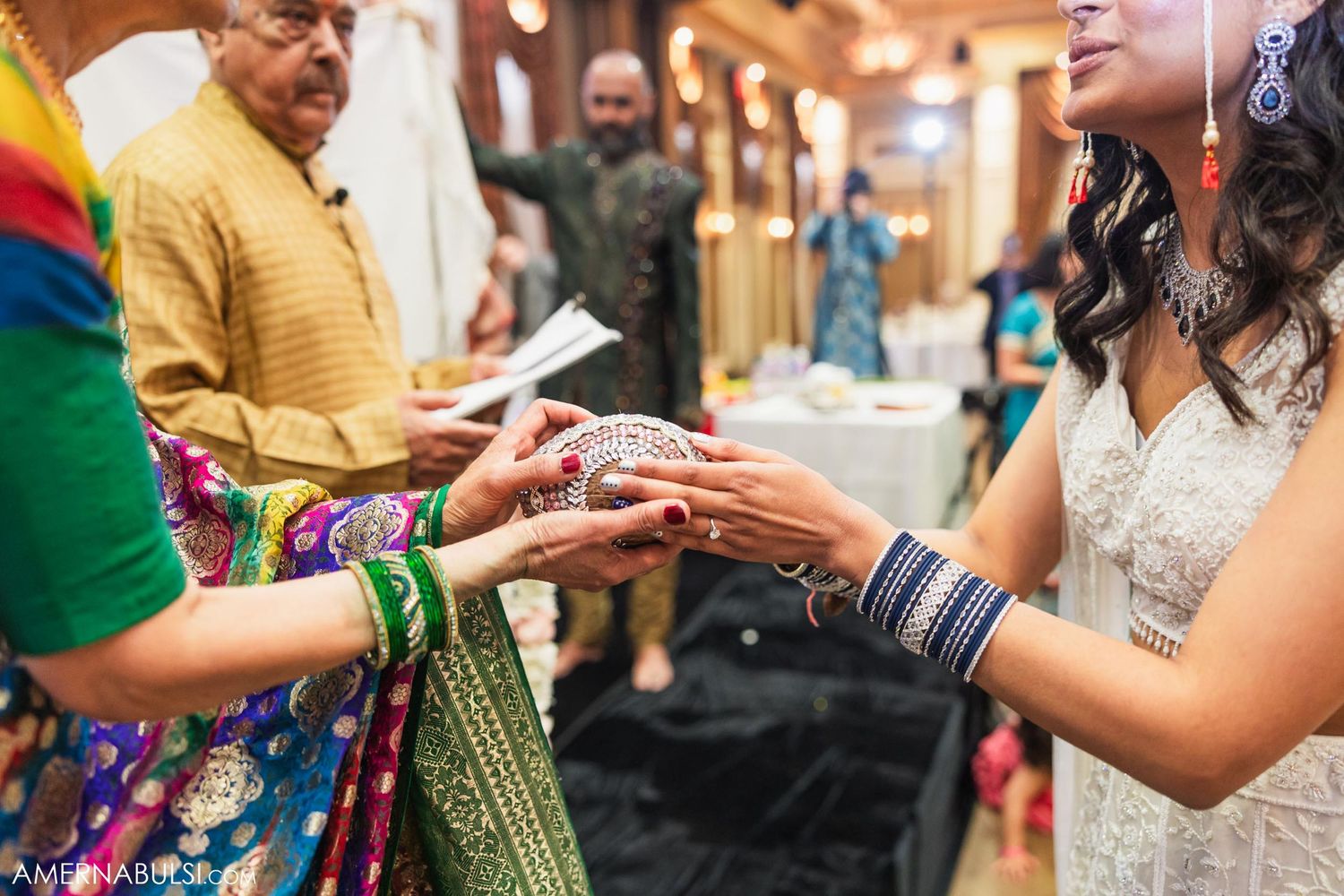 Close-up of hands during traditional wedding ritual with colorful bangles and decorative details.