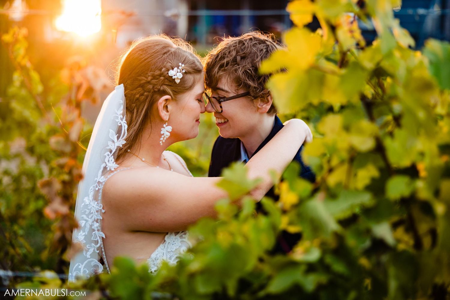 Romantic sunset moment between newlyweds among vineyard leaves.