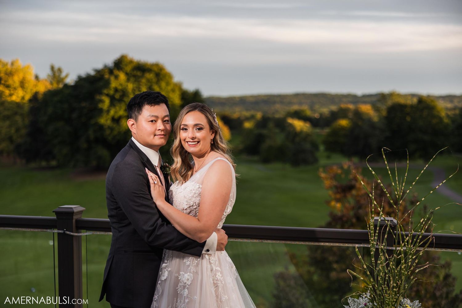 Wedding couple poses for romantic portrait on balcony overlooking scenic golf course.