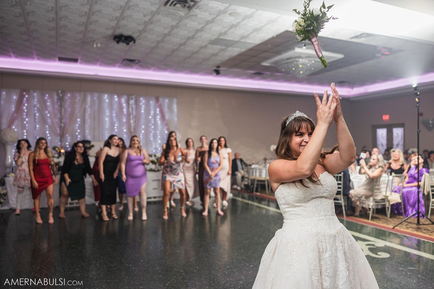 Bride preparing to toss bouquet to waiting crowd at wedding reception.