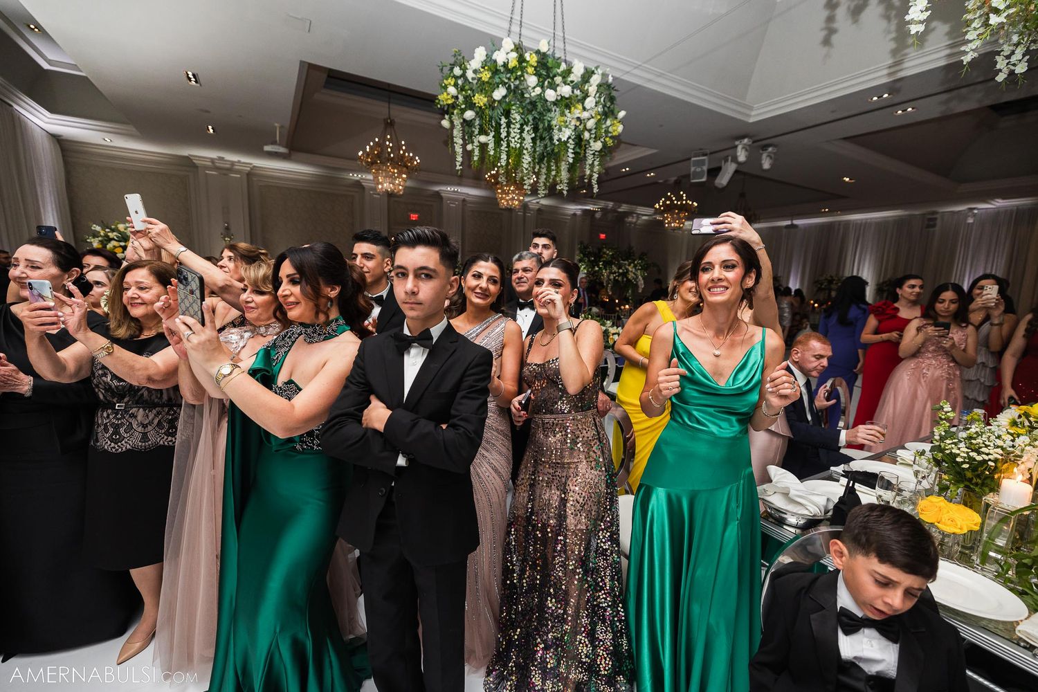 Wedding guests dancing and celebrating in formal attire at an elegant reception.