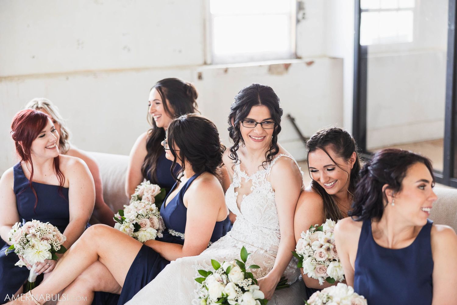 Wedding party shares candid laughing moment while seated together.
