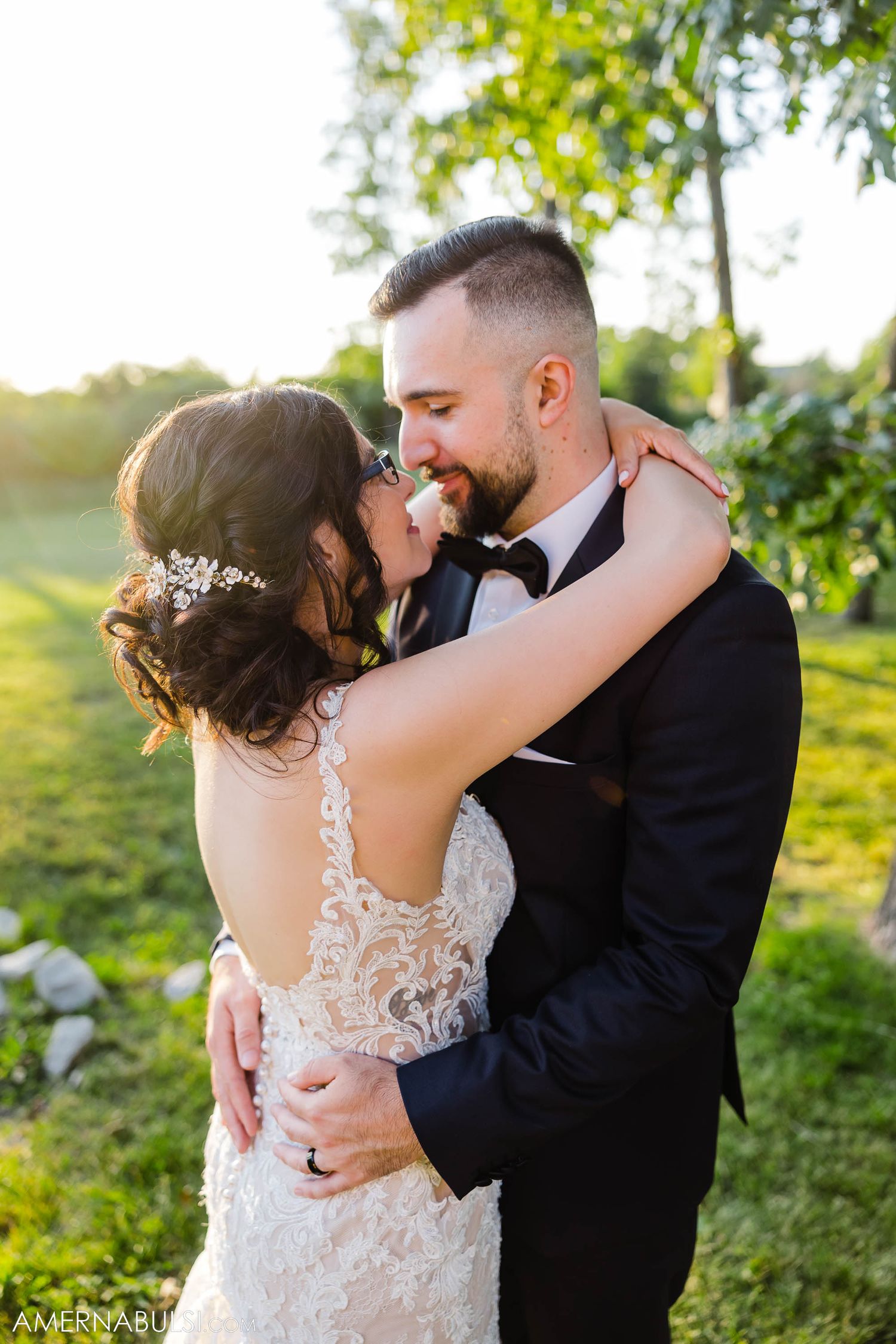 A romantic sunset embrace between newlyweds in an outdoor garden setting.