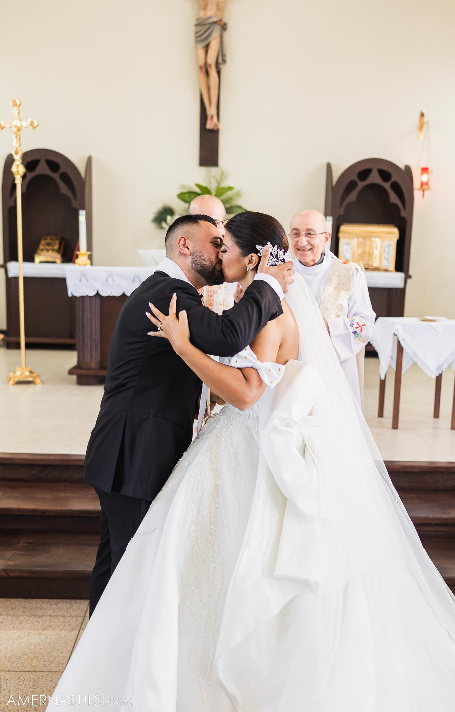 Newlyweds share their first kiss at the altar during Catholic church ceremony.