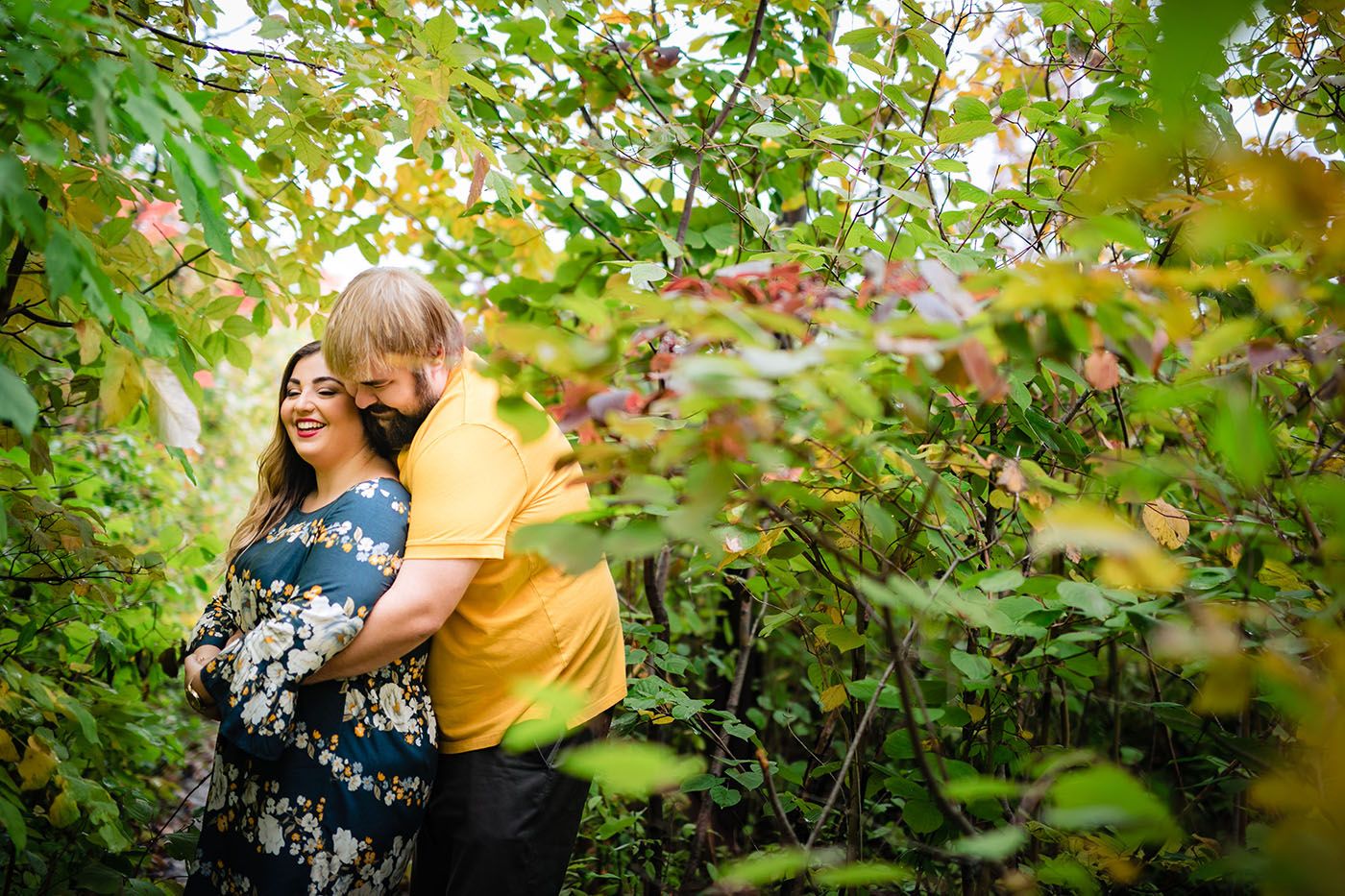 Intimate moment captured through green summer foliage in natural outdoor setting.