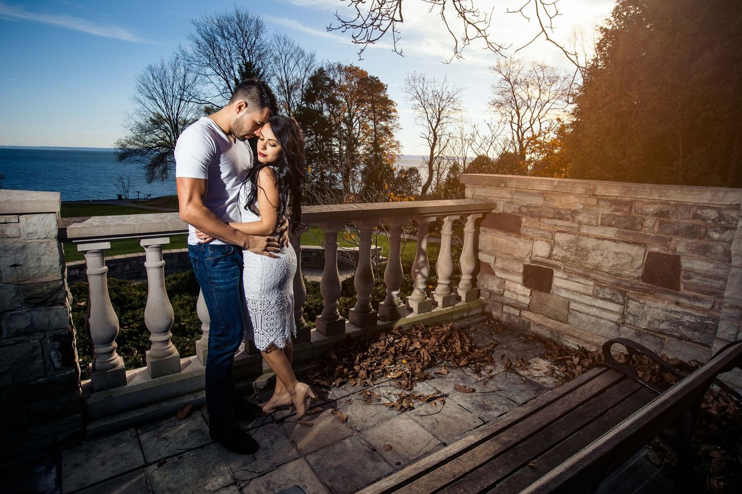 Stone balcony overlooking scenic landscape at sunset creates romantic ambiance for couple's portraits.