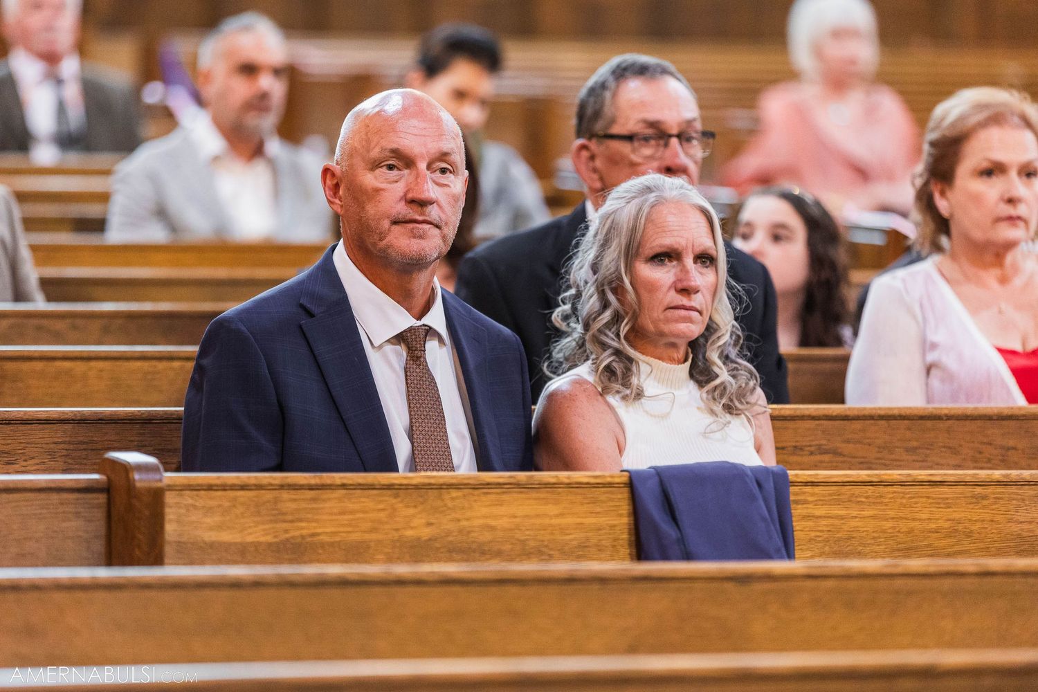 Wedding attendees seated in traditional wooden church pews.