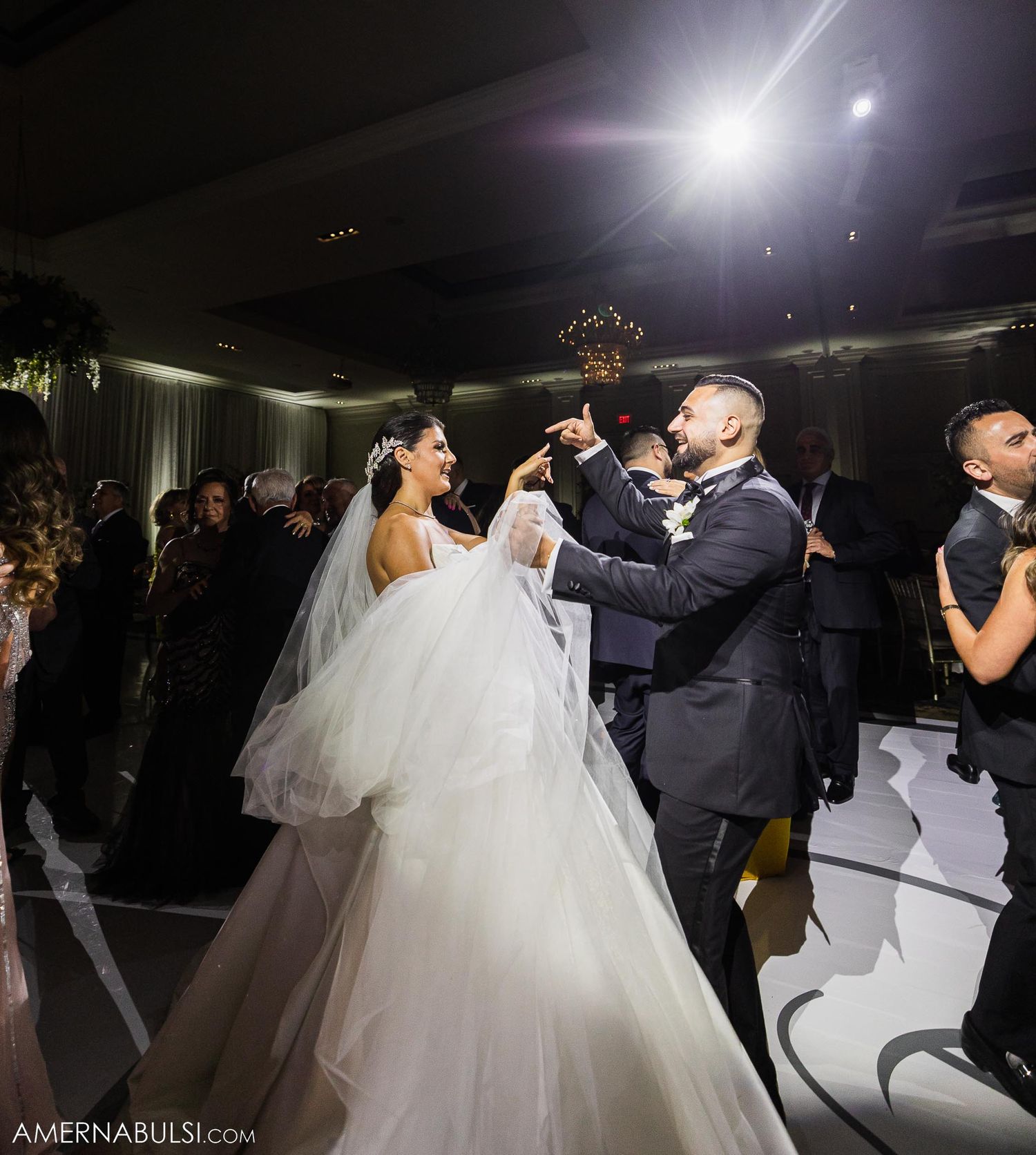 Dramatic lighting illuminates a couple's dance moment during their wedding celebration.