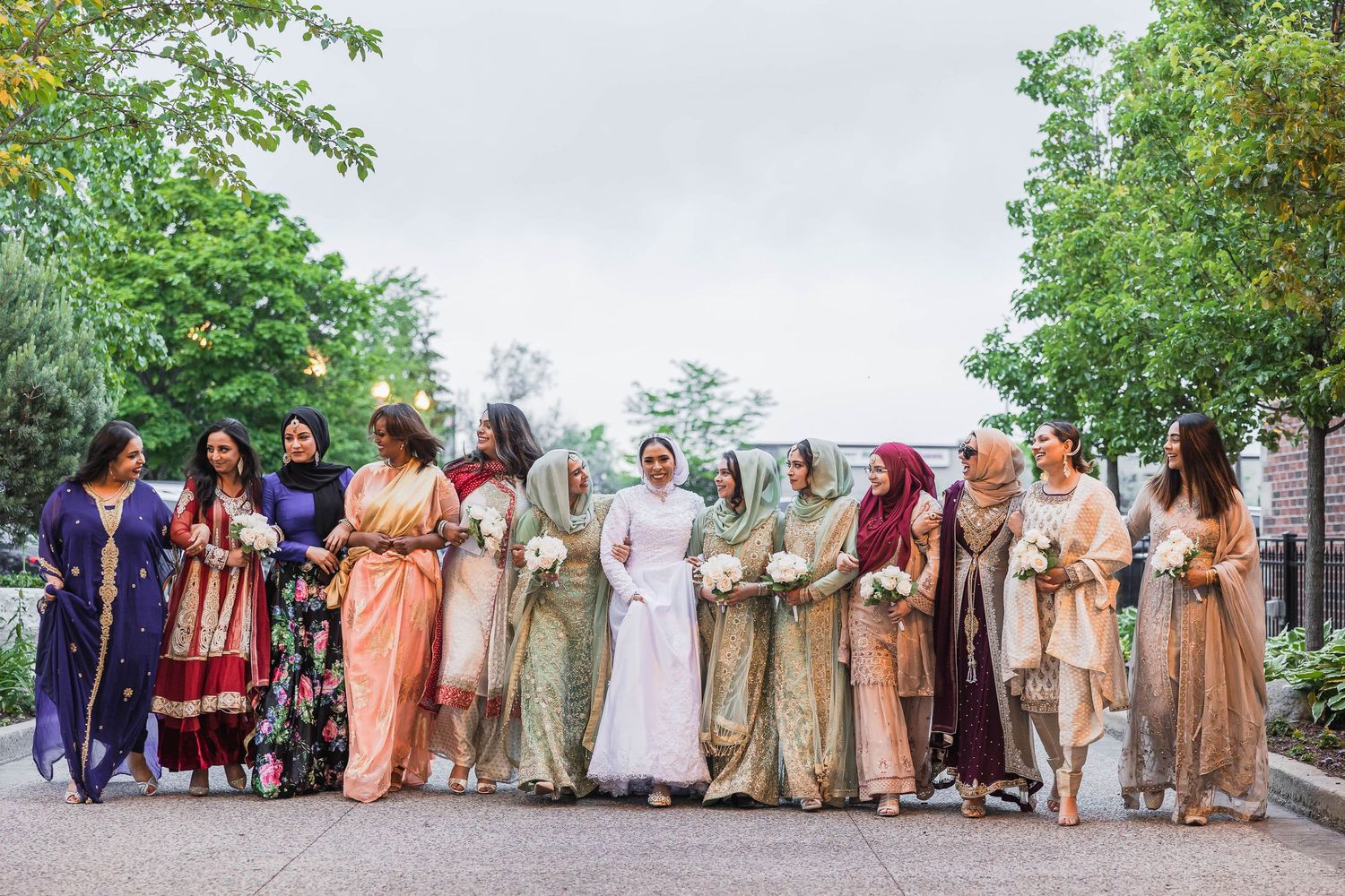 Wedding party members in traditional attire posing together outdoors.