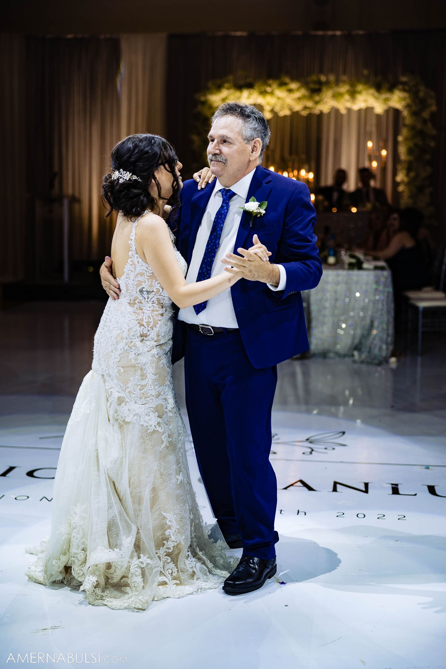 A couple shares their first dance at a wedding reception on a personalized dance floor.