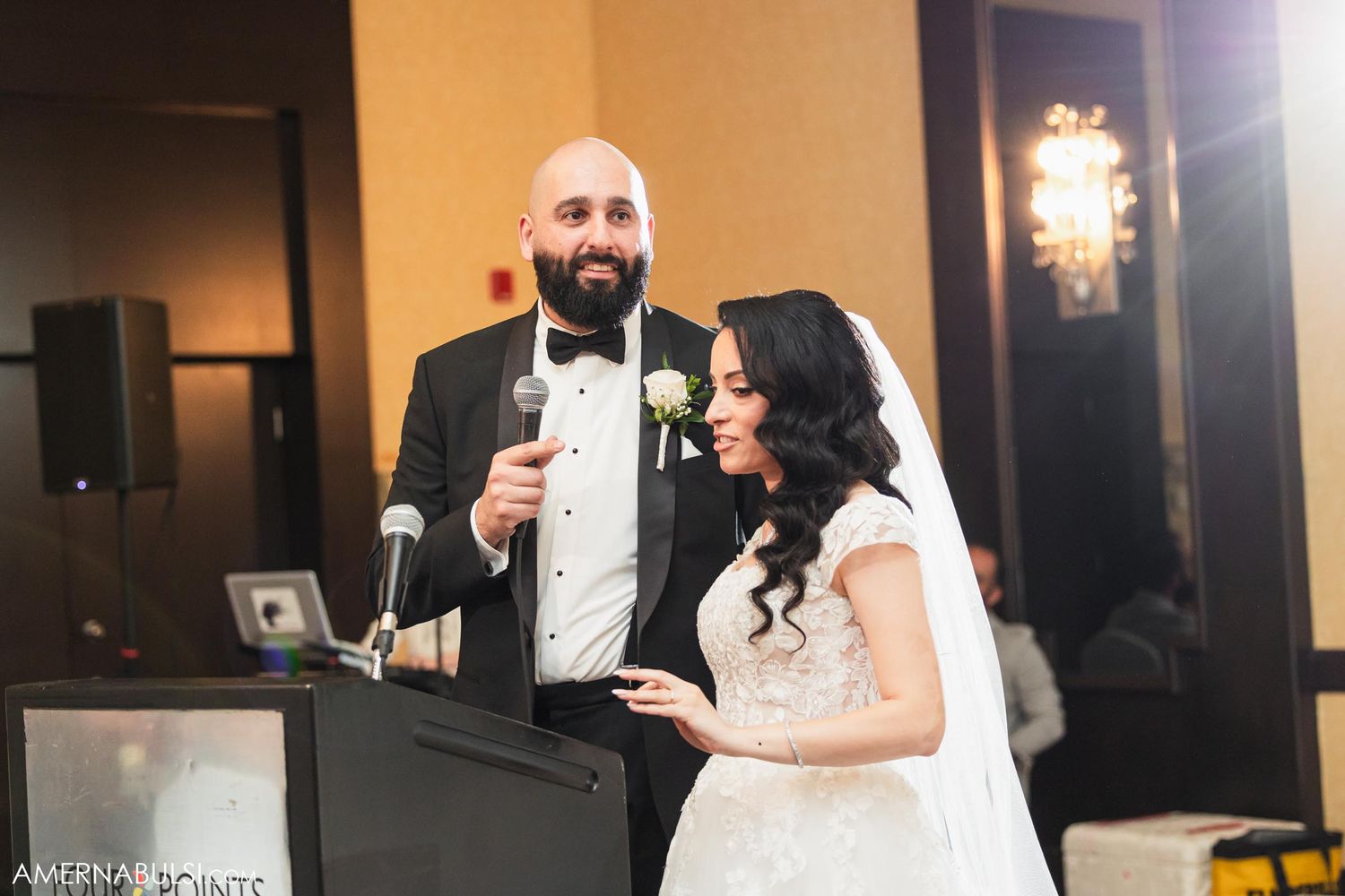 A couple in formal attire delivers a heartfelt speech at their wedding reception podium.