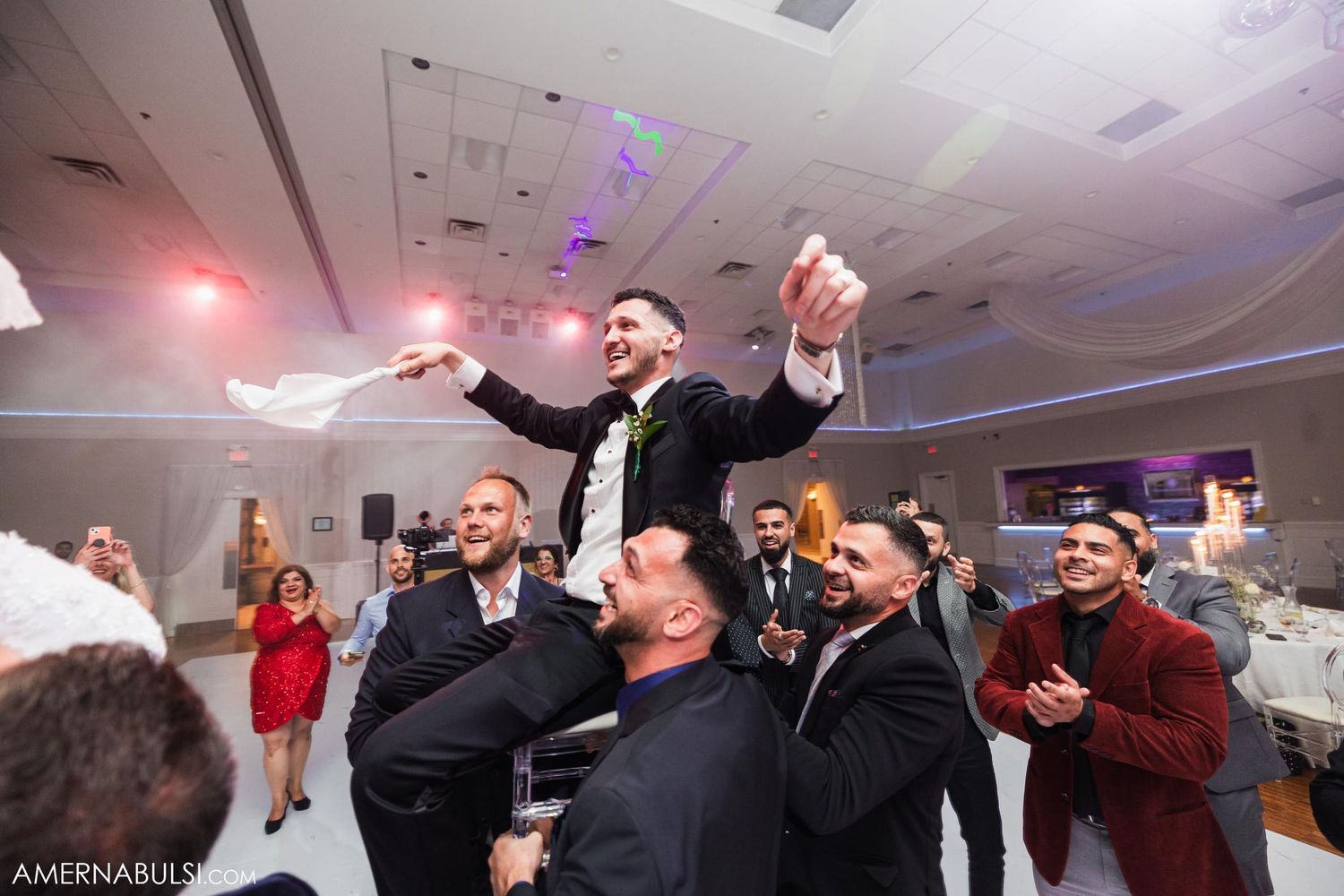 Wedding celebration with guest being lifted by friends during reception party.
