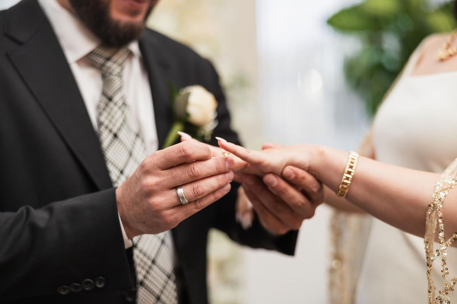 Close-up shot of hands exchanging wedding rings during ceremony.