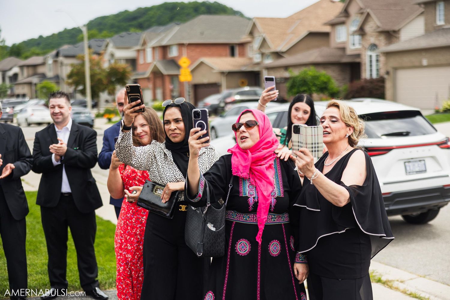 Diverse group of wedding guests enjoying outdoor celebration in suburban setting.