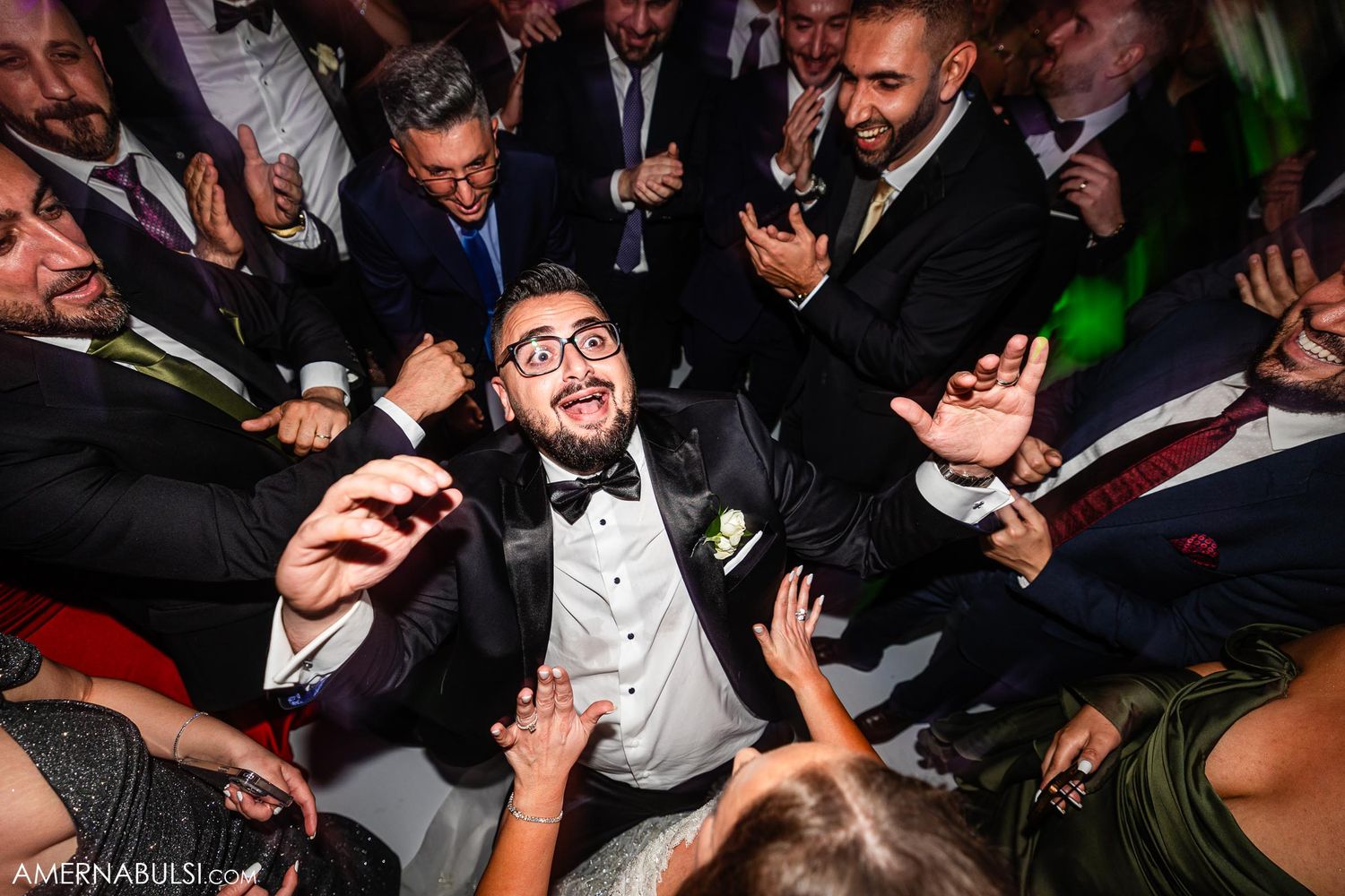 Wedding reception celebration with guests dancing under colorful party lights.