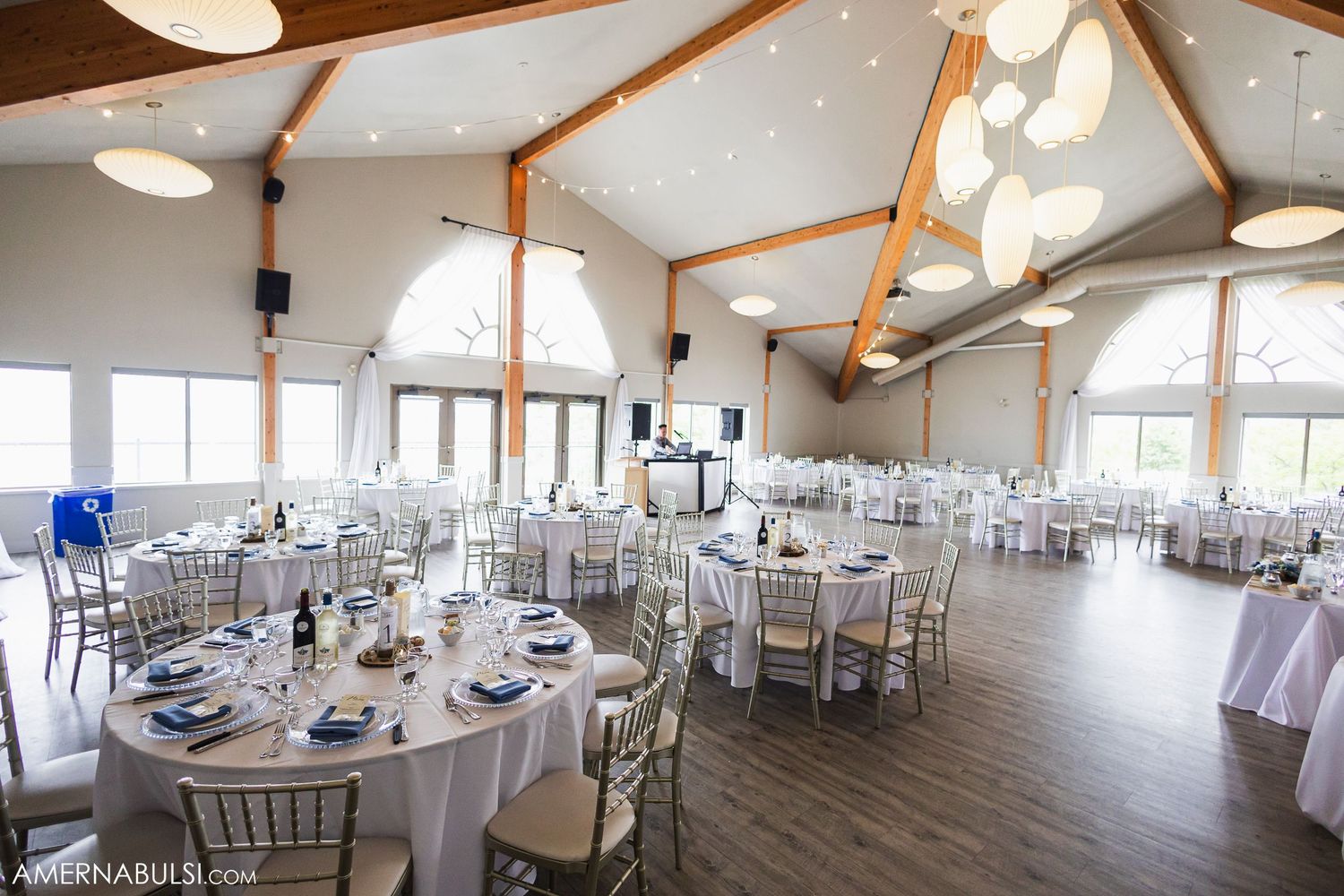 Spacious white wedding reception venue with vaulted ceilings and elegant table settings.