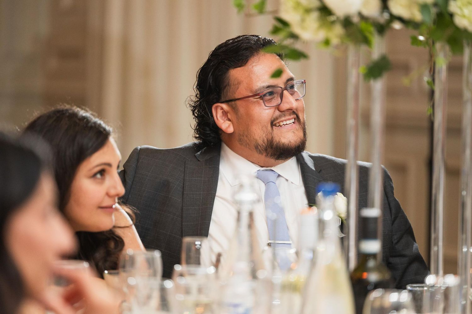 A guest smiles during the wedding reception dinner surrounded by elegant decor.