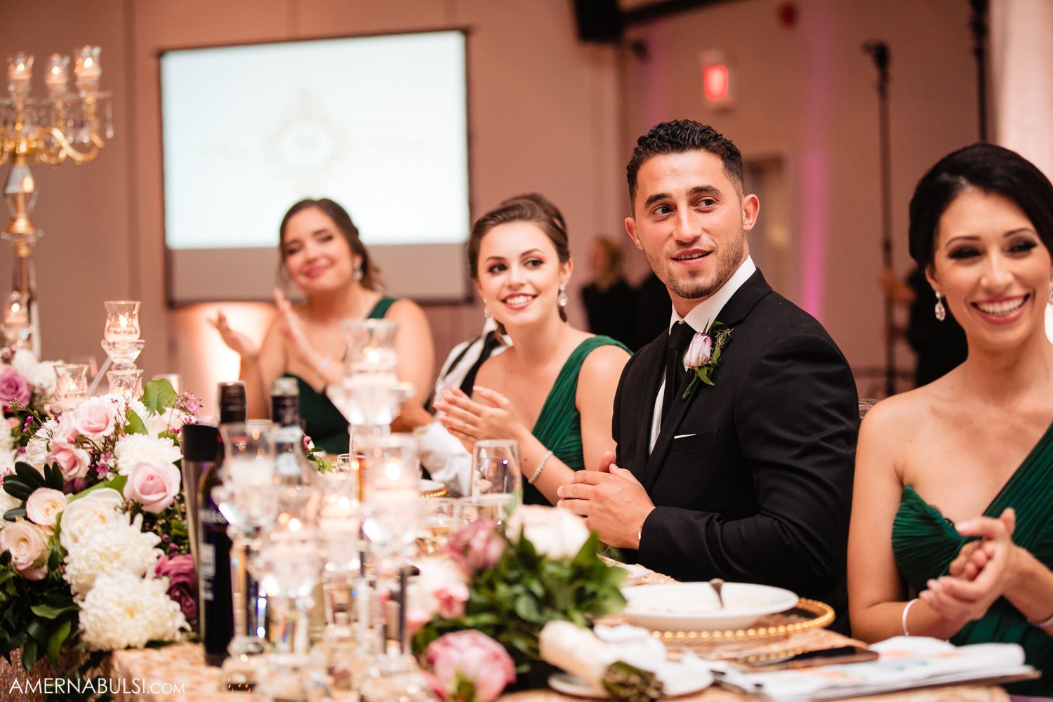 Wedding reception dinner features elegant table settings with floral centerpieces and crystal chandeliers.