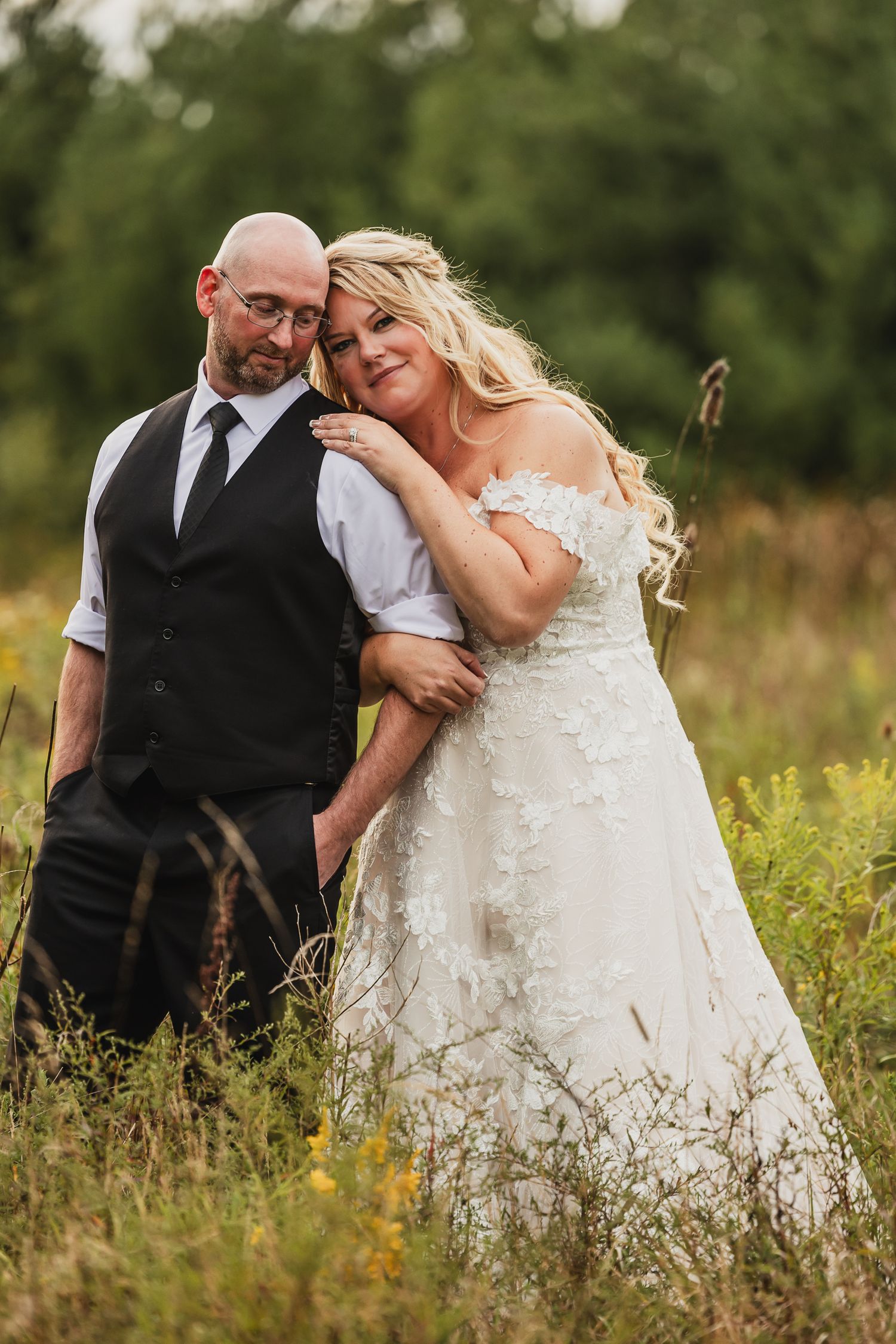 Wedding couple shares tender moment in wildflower field with soft natural lighting.