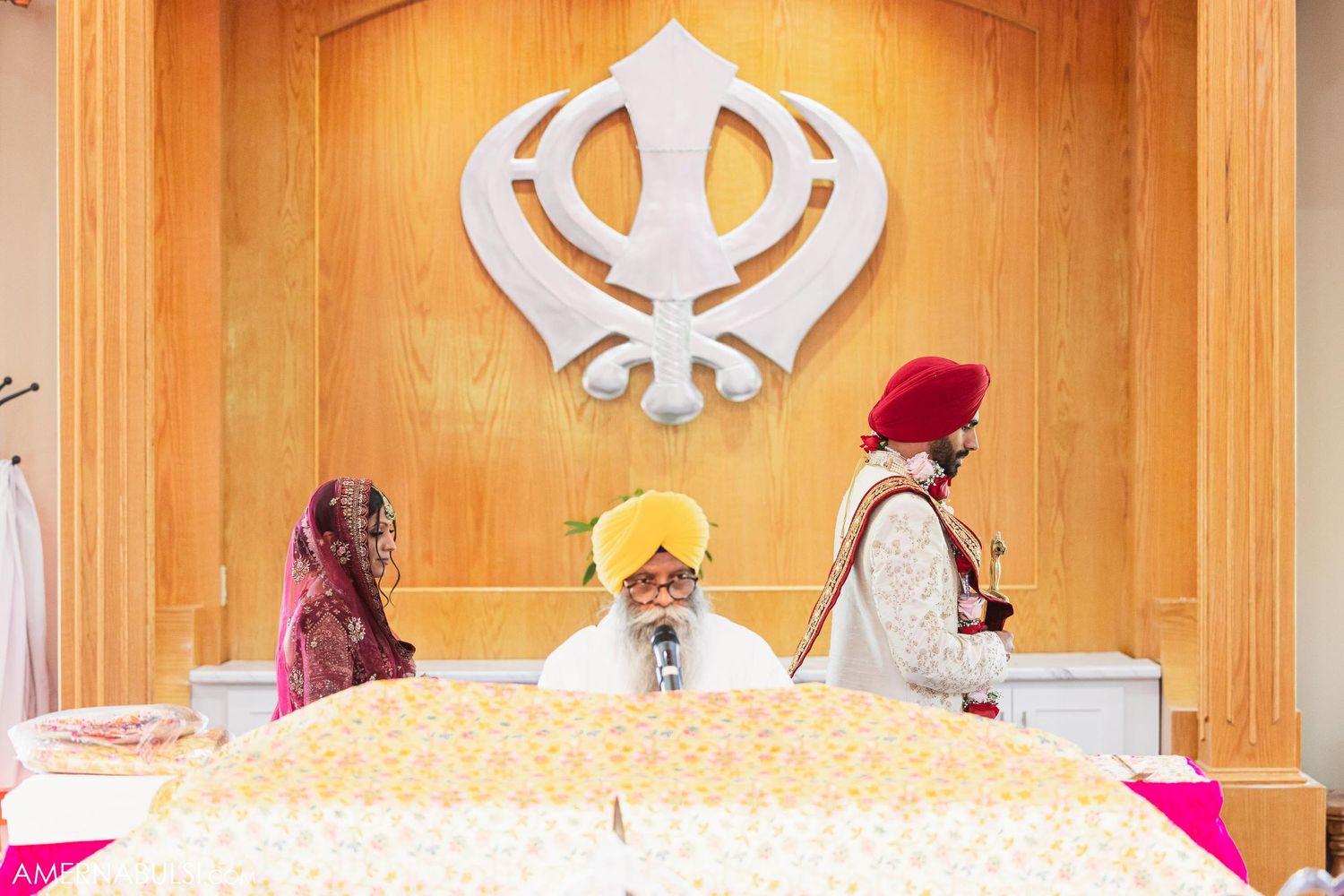 Traditional Sikh wedding ceremony with Khanda symbol and sacred text on decorated altar.