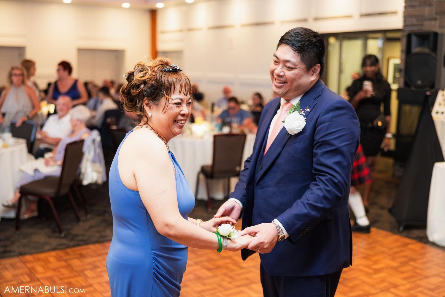 Wedding guests share joyful moment while dancing on parquet floor.